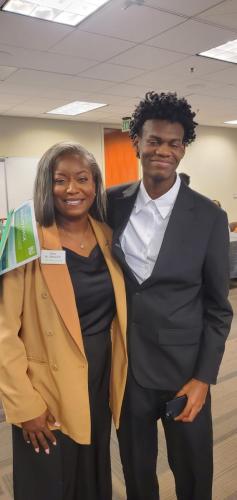 Two people smiling in business attire, exuding financial literacy under fluorescent lights with a green exit sign.