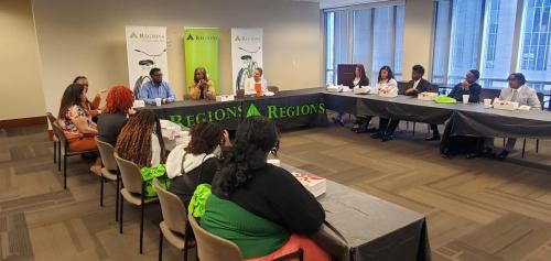 People seated around a U-shaped table in a Regions-branded conference room, discussing financial literacy.