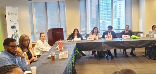 People seated around a conference table with boxed meals, engaged in a discussion on financial literacy.