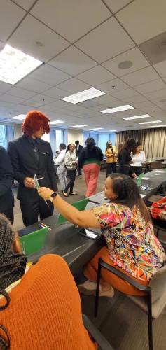 People engaging in conversations about financial literacy around tables in an office setting, some standing and some seated.